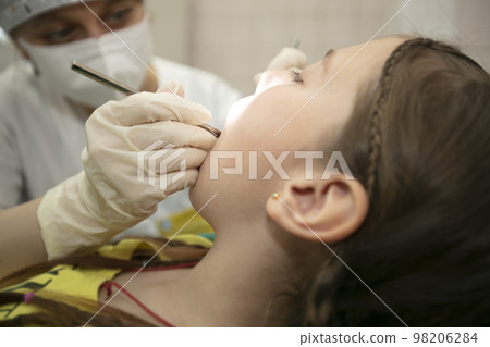The child is being treated for teeth in the dental office.Child in the dentist office 98206284