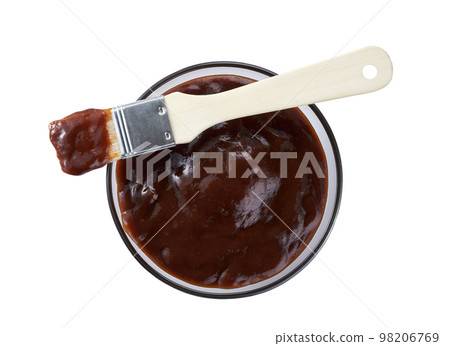 Barbecue sauce in bowl with barbecue brush isolated on a white background, top view. Barbecue sauce in bowl with barbecue brush isolated on a white background, top view. 98206769