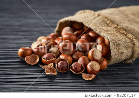 hazelnut are poured out of the bag on a black table, close-up. hazelnut are poured out of the bag on a black table, close-up. 98207117