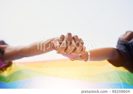 LGBTQ flag, rainbow and couple holding hands for gay pride, lesbian support or human rights protest. LGBT community, sky and African black people together in love, partnership and equality below view LGBTQ flag, rainbow and couple holding hands for gay pride, lesbian support or human rights protest. LGBT community, sky and African black people together in love, partnership and equality below view 98208604