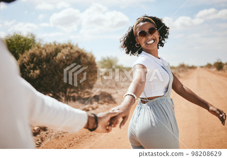 Couple, walking and nature with a black woman and man outdoor holding hands on a sand road in a dessert together. Travel, love and romance with a female and male on a date during summer vacation Couple, walking and nature with a black woman and man outdoor holding hands on a sand road in a dessert together. Travel, love and romance with a female and male on a date during summer vacation 98208629