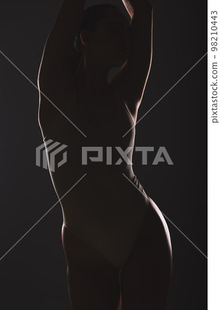 Silhouette, beauty and woman in studio on dark background for cosmetics, wellness and sensual aesthetic. Creative art, fashion and torso of girl model pose for satisfaction, body care and figure 98210443