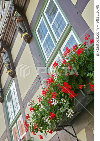 Quaint village life. Flowers decorating a window exterior on an old building- low angle. 98211649