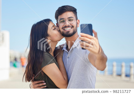 Phone, kiss or couple love taking a selfie on a romantic honeymoon, beach holiday or vacation in a summer romance. Smile, profile pictures or happy man enjoys quality bonding time with Indian partner Phone, kiss or couple love taking a selfie on a romantic honeymoon, beach holiday or vacation in a summer romance. Smile, profile pictures or happy man enjoys quality bonding time with Indian partner 98211727