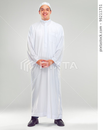 Islamic man, religion fashion and standing for worship, prayer or spiritual happiness in white background. Arabic person, smile and happy respect for muslim culture or clothes isolated in studio 98211751