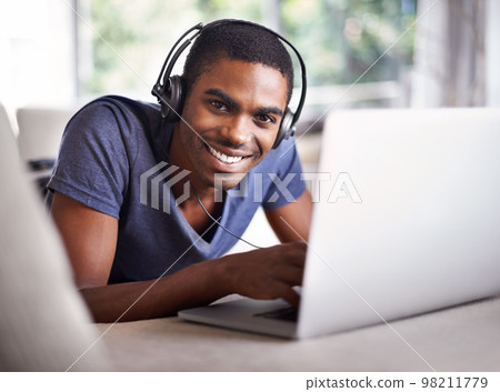 Relaxing while getting some work done this weekend. a handsome young man using his laptop while relaxing at home. Relaxing while getting some work done this weekend. a handsome young man using his laptop while relaxing at home. 98211779