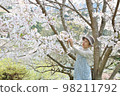 Senior woman lifting a branch of cherry blossoms and looking at the flowers Knee up 98211792