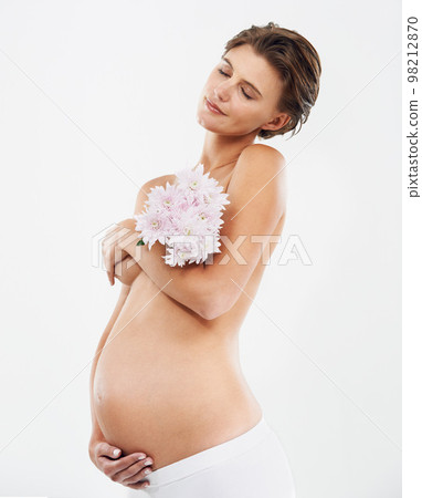 Pregnancy, calm and woman with flowers in a studio holding her stomach with love, care and happiness. Feminine, maternity and pregnant female model with a floral bouquet isolated by white background. 98212870