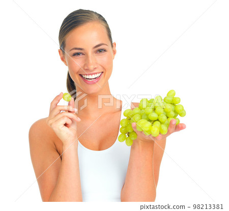 Health, wellness and woman with grapes in a studio for a healthy snack, nutrition diet or craving. Wellbeing, weightloss and portrait of young female model eating fruit isolated by a white background Health, wellness and woman with grapes in a studio for a healthy snack, nutrition diet or craving. Wellbeing, weightloss and portrait of young female model eating fruit isolated by a white background 98213381