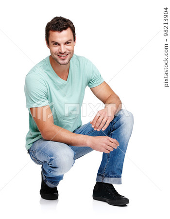 Happy, smile and portrait of a man in a studio with a casual, stylish and cool trendy outfit. Handsome, young and male model with natural fashion clothes crouching while isolated by white background. 98213904