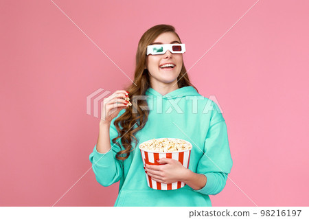 woman watching comedy holding bucket of popcorn 98216197