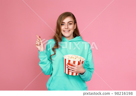 woman in sweatshirt watching movie film, eating popcorn 98216198