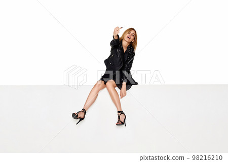 blonde woman with long legs sitting on white bench. blonde woman with long legs sitting on white bench. 98216210