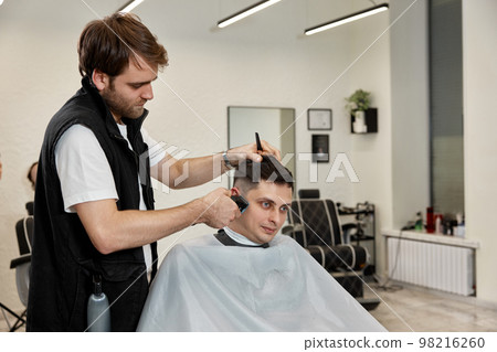 Barber shaving caucasian man in barber shop. Barber shaving caucasian man in barber shop. 98216260
