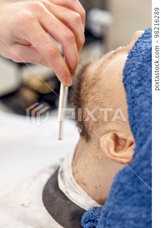 Barber shaving bearded man in barber shop. 98216289