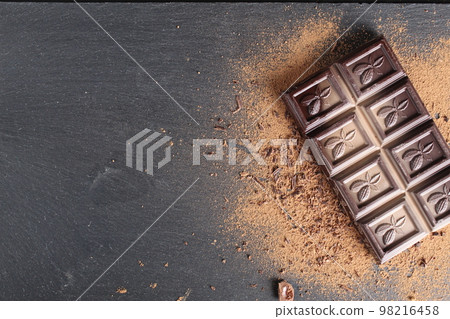 Chocolate bar sprinkled with cocoa chocolate crumb on black grey background with meth copy space 98216458