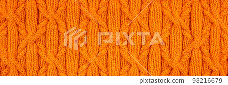 Knitted orange background. Large knitted fabric with a pattern. Close-up of a knitted blanket. Banner Knitted orange background. Large knitted fabric with a pattern. Close-up of a knitted blanket. Banner 98216679