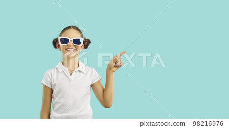 Caucasian girl teen in funny sunglasses with smile points finger at copy space in turquoise studio Caucasian girl teen in funny sunglasses with smile points finger at copy space in turquoise studio 98216976