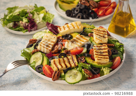 Greek style cuisine - salad with grilled halloumi cheese, avocado, pecan nuts and tomatoes. Greek style cuisine - salad with grilled halloumi cheese, avocado, pecan nuts and tomatoes. 98216988