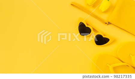 top view with copy space of flip flops and sunglasses with lily on yellow background. 98217335