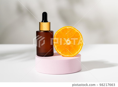 Serum bottle with dropper and slice of orange, ingredients for skin care and treatment vitamin. 98217663