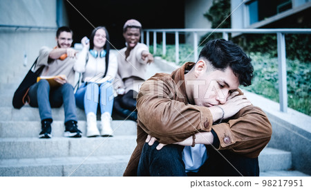 A group of students bulling an hispanic man sitting on the stairs outdoors A group of students bulling an hispanic man sitting on the stairs outdoors 98217951