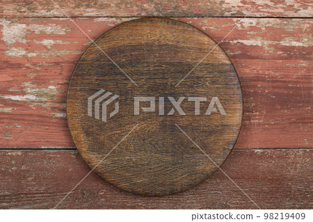 Circle cutting board on a red wooden table. Food preparation tool and kitchen utensils. Circle cutting board on a red wooden table. Food preparation tool and kitchen utensils. 98219409