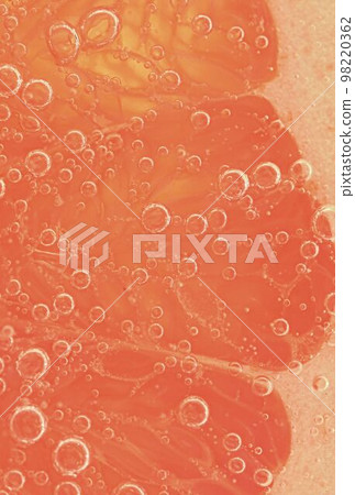 Red grapefruit slice floating in club soda. Fresh grapefruit slice with bubbles in carbonated drink. Fresh natural red grapefruit slice covered by bubbles 98220362
