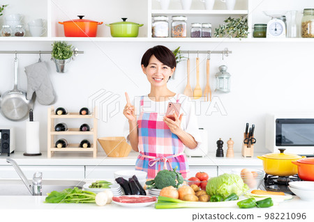 Middle-aged housewife in the kitchen Middle-aged housewife in the kitchen 98221096