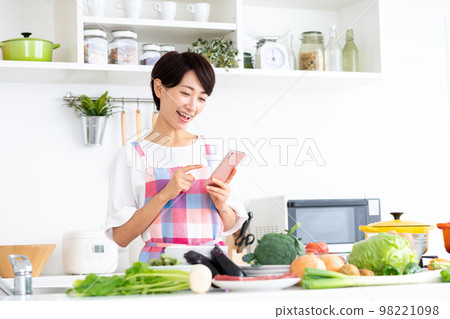 Middle-aged housewife in the kitchen Middle-aged housewife in the kitchen 98221098