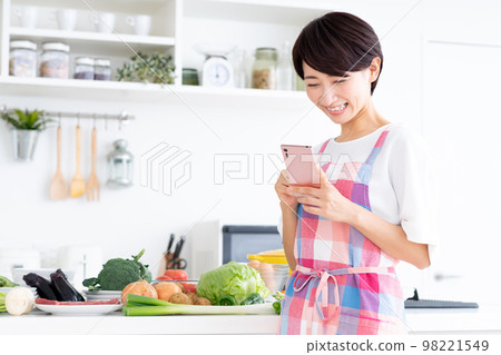 Middle-aged housewife in the kitchen Middle-aged housewife in the kitchen 98221549