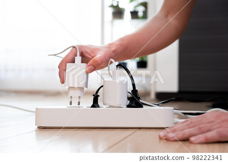 Man plugs in the electric charger. Energy savings 98222341