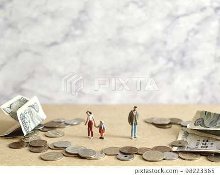 Dolls of a woman, a child and a man holding hands and money around them 98223365