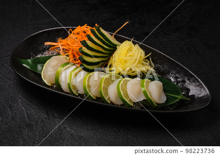 Scallop sashimi with vegetables on black background Scallop sashimi with vegetables on black background 98223736