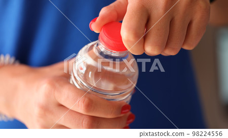 Woman opens plastic bottle with water closeup Woman opens plastic bottle with water closeup 98224556