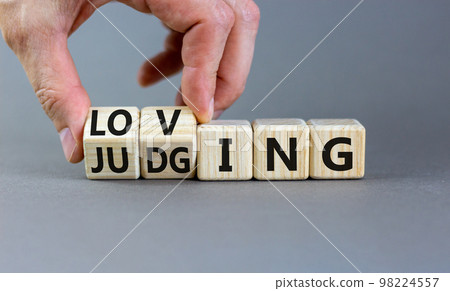 Loving or judging symbol. Concept words Loving or Judging on wooden cubes. Businessman hand. Beautiful grey table grey background. Business loving or judging concept. Copy space. Loving or judging symbol. Concept words Loving or Judging on wooden cubes. Businessman hand. Beautiful grey table grey background. Business loving or judging concept. Copy space. 98224557