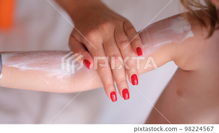 Woman applies cream on red skin of child hands Woman applies cream on red skin of child hands 98224567