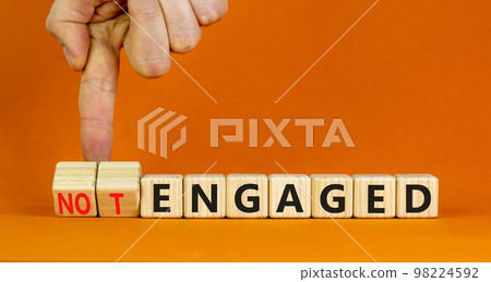 Engaged or not symbol. Concept words Engaged and Not engaged on wooden cubes. Businessman hand. Beautiful orange table orange background. Business engaged or not engaged concept. Copy space. 98224592