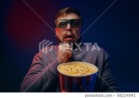 A man watches horror movies. The emotion of fear. A man watches horror movies. The emotion of fear. 98224841
