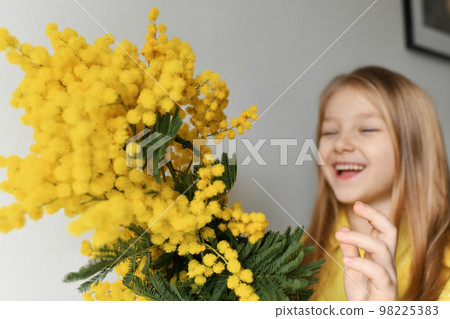A girl smelling yellow mimosa at spring A girl smelling yellow mimosa at spring 98225383