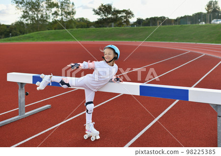 A girl in vintage white roller skates and a helmet at the stadium 98225385