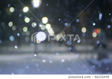Blurred background. City view, lights, falling snow, night, street, bokeh spots of headlights of moving cars. Diffuse Urban backdrop winter scenery of street in city at night. Lantern light, snowfall Blurred background. City view, lights, falling snow, night, street, bokeh spots of headlights of moving cars. Diffuse Urban backdrop winter scenery of street in city at night. Lantern light, snowfall 98226446