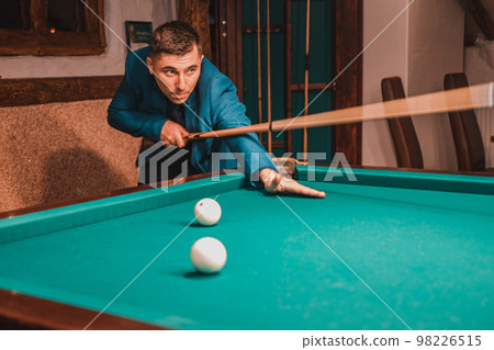 Playing billiards, a man as an amateur plays billiards, a sports board game. Playing billiards, a man as an amateur plays billiards, a sports board game. 98226515