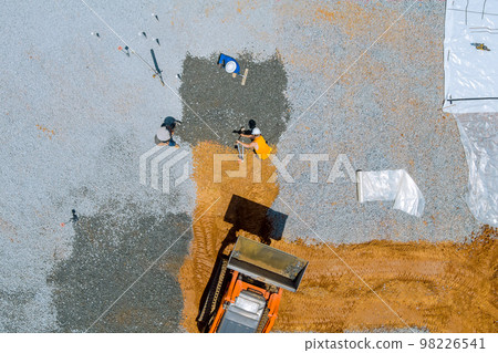 An excavator bucket used before concrete foundation is poured on site of building for purpose leveling gravel 98226541