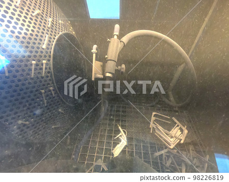 Shot blasting. Shot blasting of model printed on 3D printer from polyamide powder. A worker in sealed rubber gloves cleans the object by shot blasting in a shot blasting chamber. Industrial machine Shot blasting. Shot blasting of model printed on 3D printer from polyamide powder. A worker in sealed rubber gloves cleans the object by shot blasting in a shot blasting chamber. Industrial machine 98226819