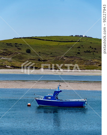 One boat is anchored in the bay at low tide, a seaside landscape. A boat in shallow water on a sunny day. Irish seascape, boat on sea. One boat is anchored in the bay at low tide, a seaside landscape. A boat in shallow water on a sunny day. Irish seascape, boat on sea. 98227943
