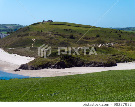 Plant-covered dunes on the coast of Ireland on a sunny spring day. Green hills. Seaside Irish landscape. The beauty of nature. Plant-covered dunes on the coast of Ireland on a sunny spring day. Green hills. Seaside Irish landscape. The beauty of nature. 98227952