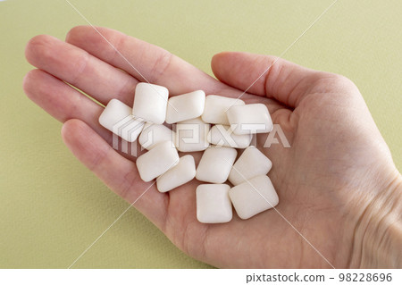Bubblegum white chewy pads in a girl's hand on a green background 98228696