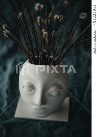 earthenware vase in the shape of a human face with willow 98228912