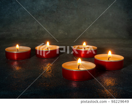 Small candles burn orange in the dark. Waiting for the holiday Small candles burn orange in the dark. Waiting for the holiday 98229649